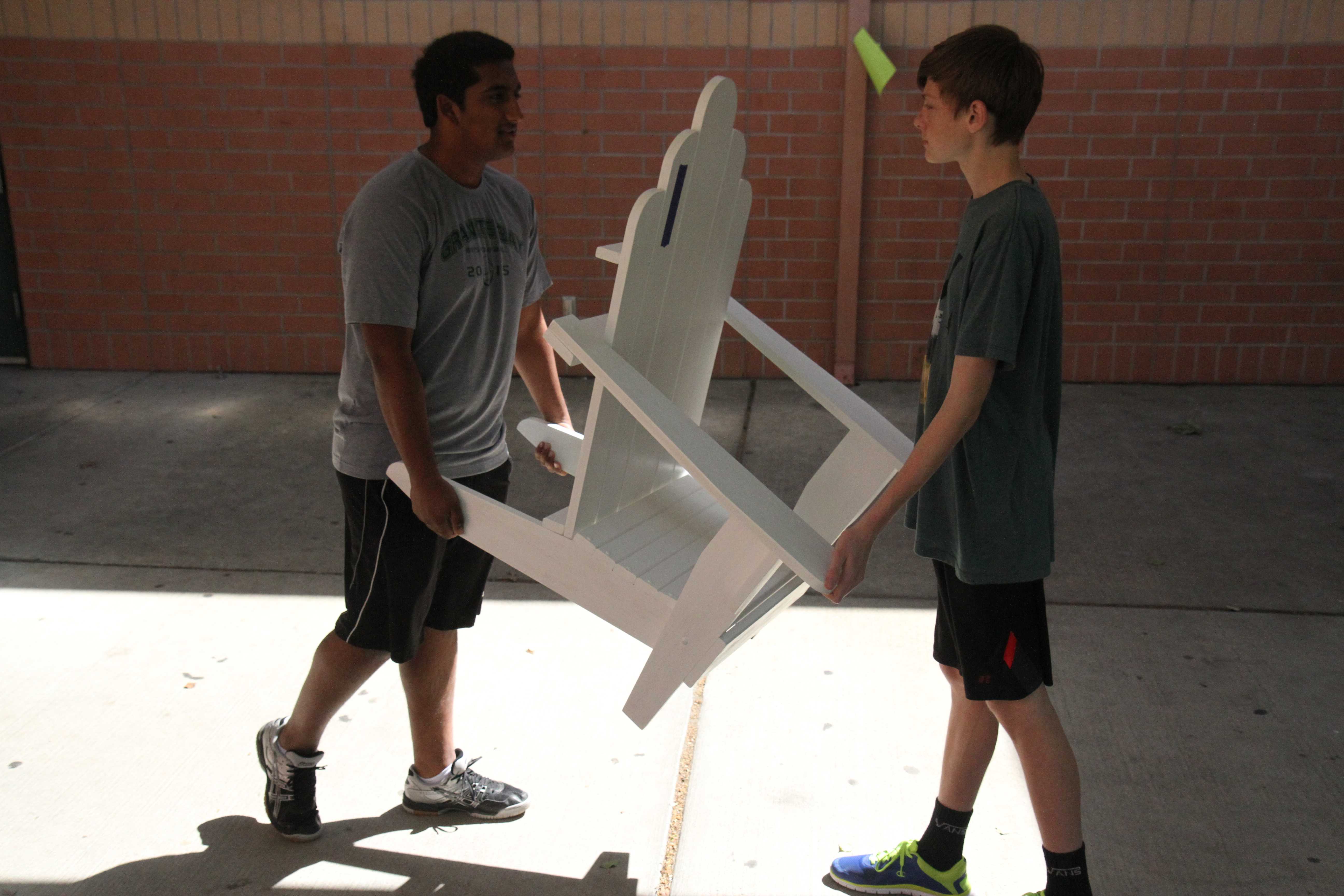 To take home the chair he made, sophomore Tyler Gregory, with his friend Rohan Dhamejani, carry the chair across campus. Gregory made the chair in woodshop, a class he loves because he can express himself and make what he wants. “It took me six weeks to make my chair, and it’ll go on the patio at my house,” Gregory said. Photo by Ava Lindley