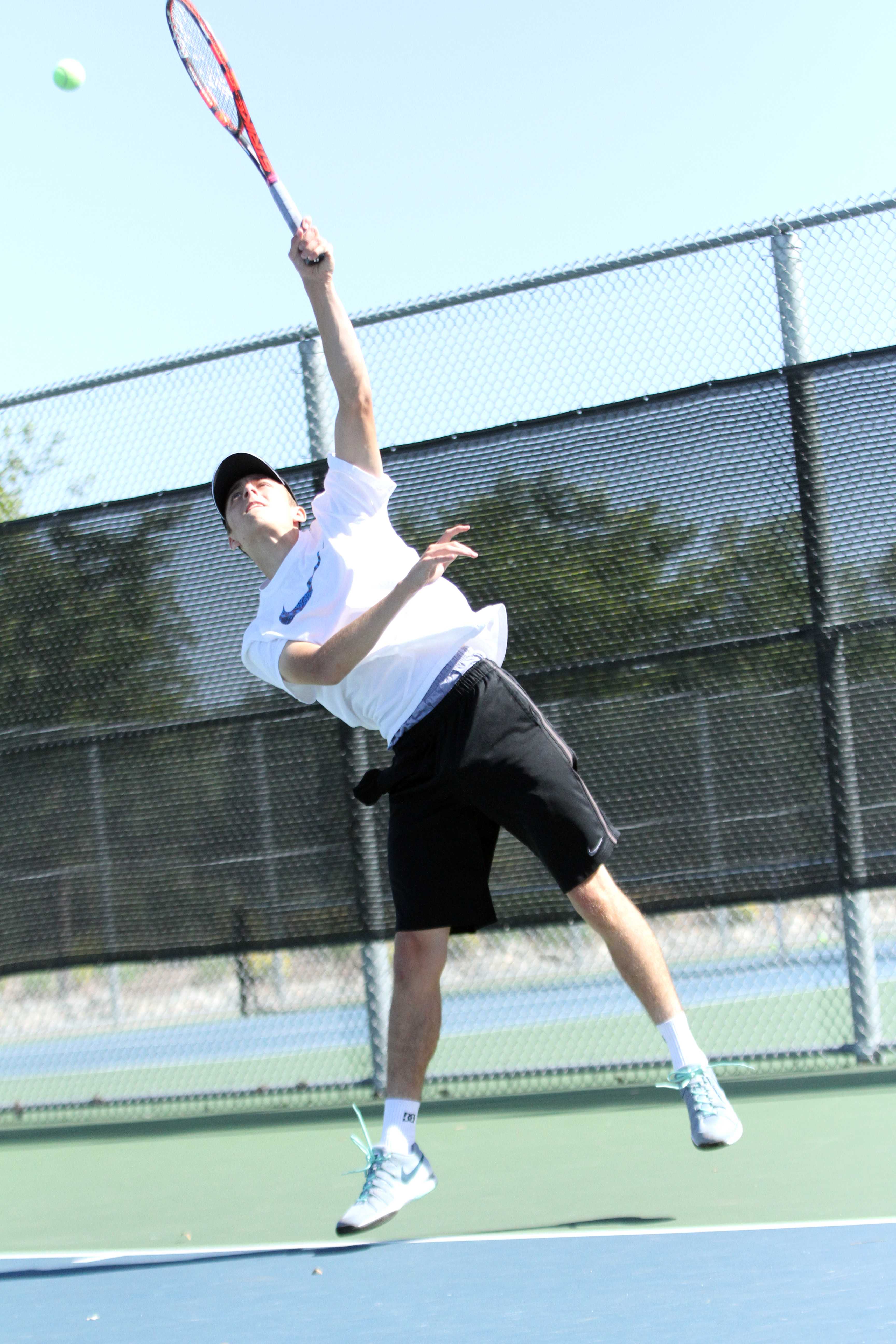 To hit a perfect serve, sophomore Austen Berry strikes confidently to make the ball over the net to practice games during their 3:00 p.m. practice on April 15. According to Berry, you must plan ahead of time and not improvise during the match. “Adjust yourself if needed to play well,” Berry said. Photo by David Goni
