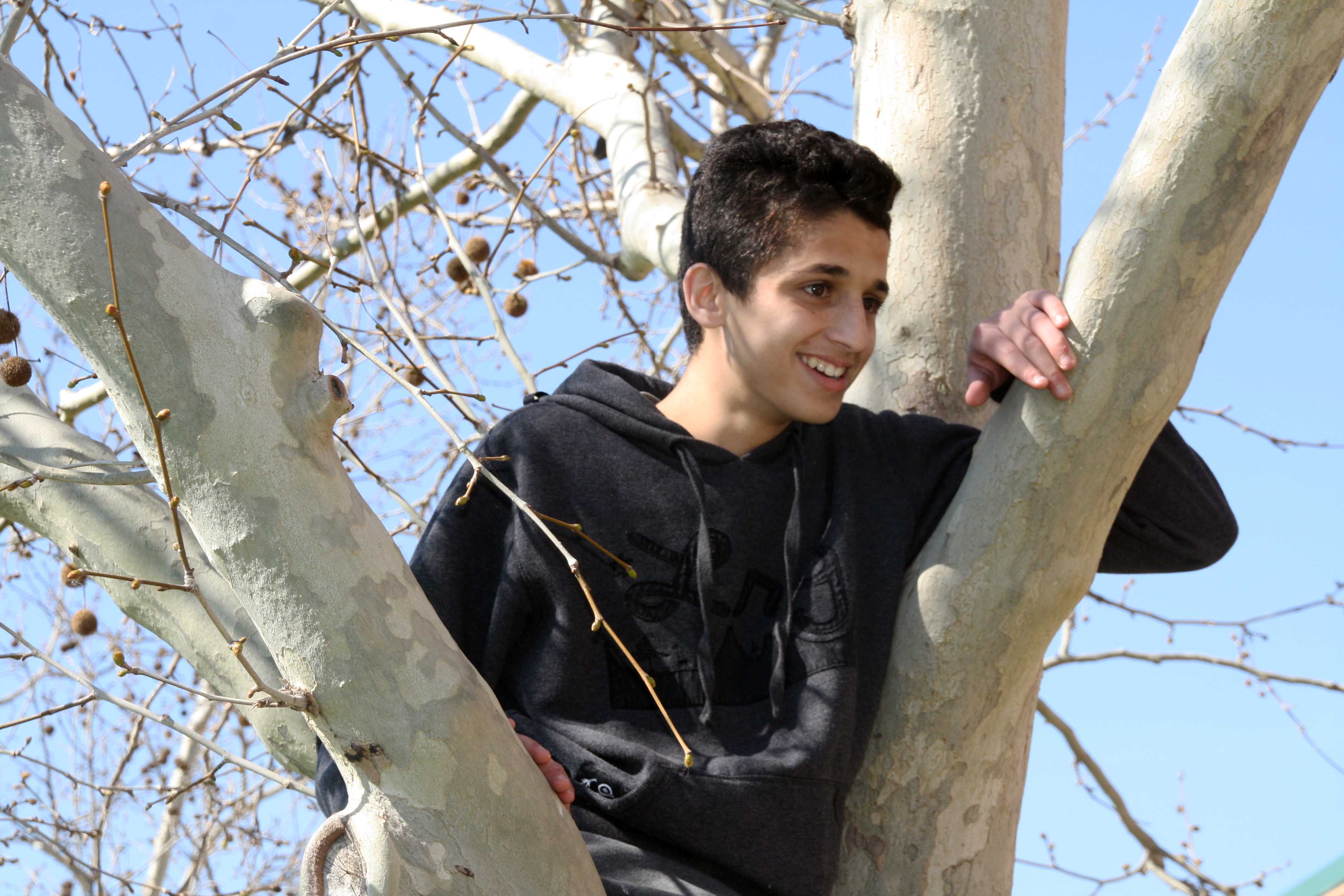Out shooting for photography freshman Ramzi Taha climbs into a tree to pose for other students in the class so they could get their shots for the project that they have to turn in soon. For the project they were working on they were required to show different photography compositions Taha climbed the tree in order to model framing. Photo by Hannah Bociek
