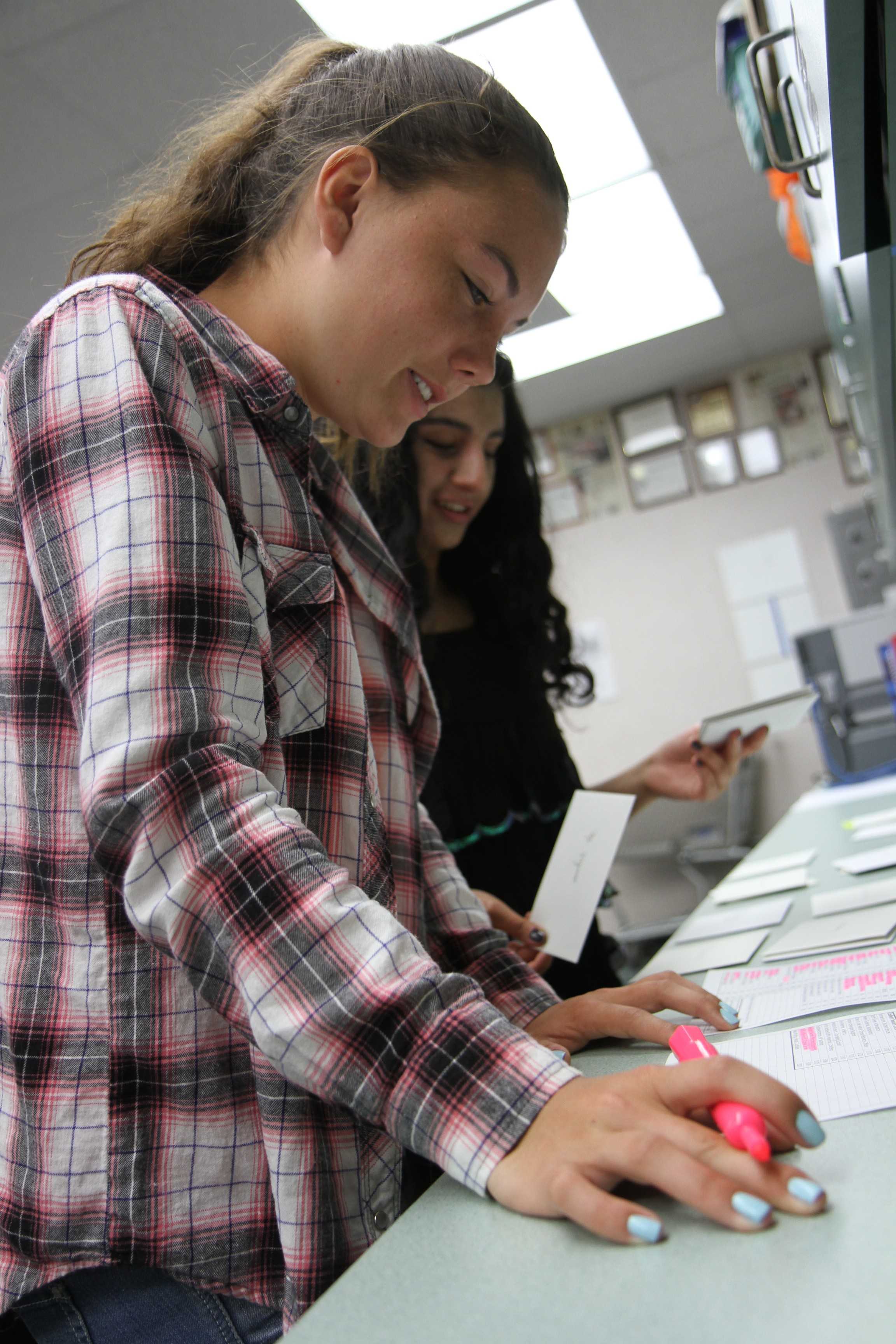 In Mrs. Bernadette Cranmer’s yearbook class, staff member Lindsay Withrow (9) and Ambreen Siddiqui (11) help each other sort thank you letters to all of the teachers in alphabetical order. As the making of the 2014-2015 yearbook comes to an end, the whole staff wrote 113 letters collectively. Some of the staff feel like they are giving teachers recognition for the extra effort and support, for without them Ursus would’ve never been able to finish the book. “It felt good to give [the teachers and staff] thank you letters because it’s saying ‘thanks for putting up with us’ because we pull their students out during class throughout the year,” Siddiqui said. Photo by Janelle Cruz