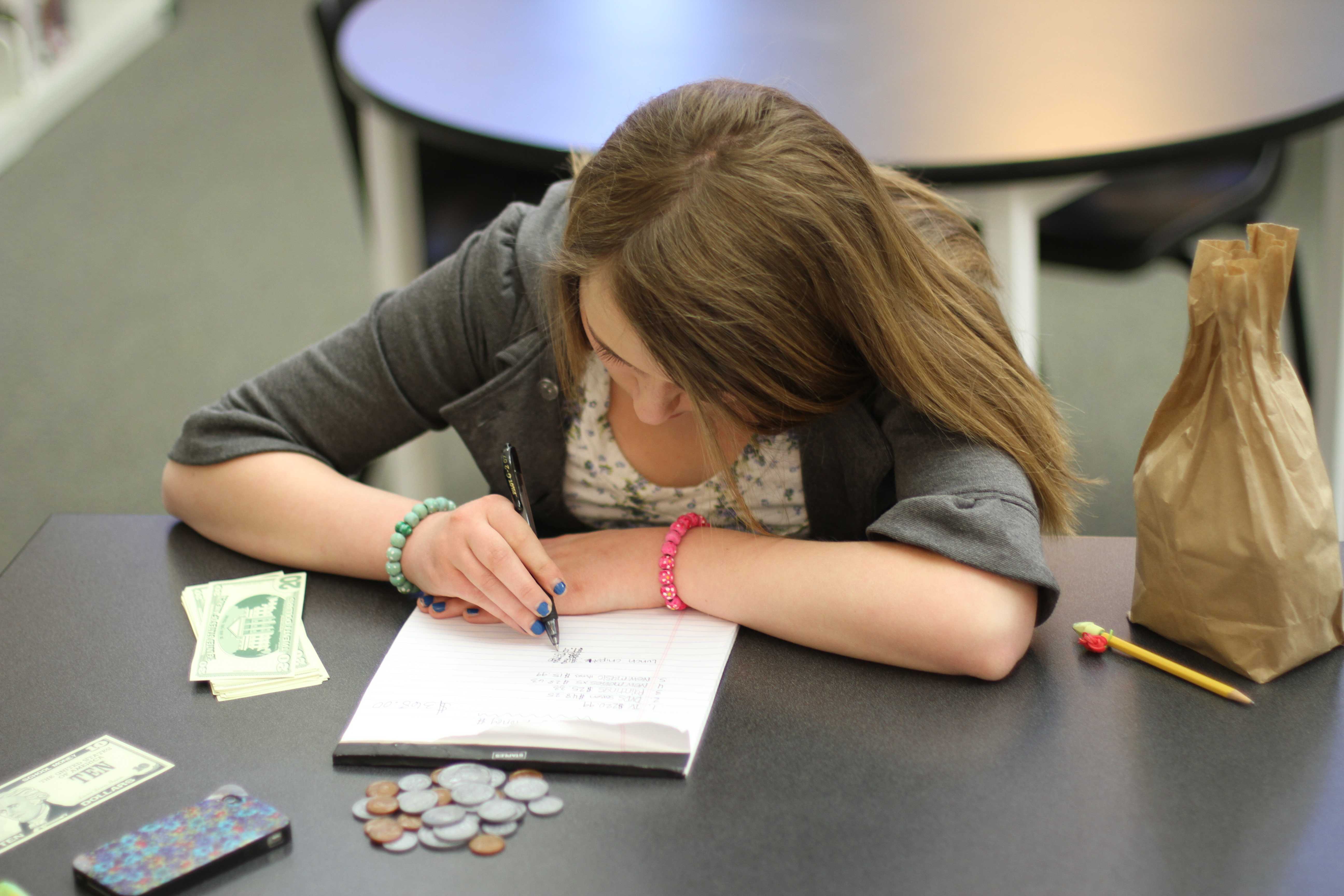 In the library first period, sophomore Morgan Ransdell works on her math skills. Although math isn’t her favorite subject, she practices her money math skills by solving problems and using plastic coins and fake paper money. “It’s to help you get ready for graduation and see if you can get a good degree in math and other school subjects too,” Ransdell said. Photo by Reese Richmond