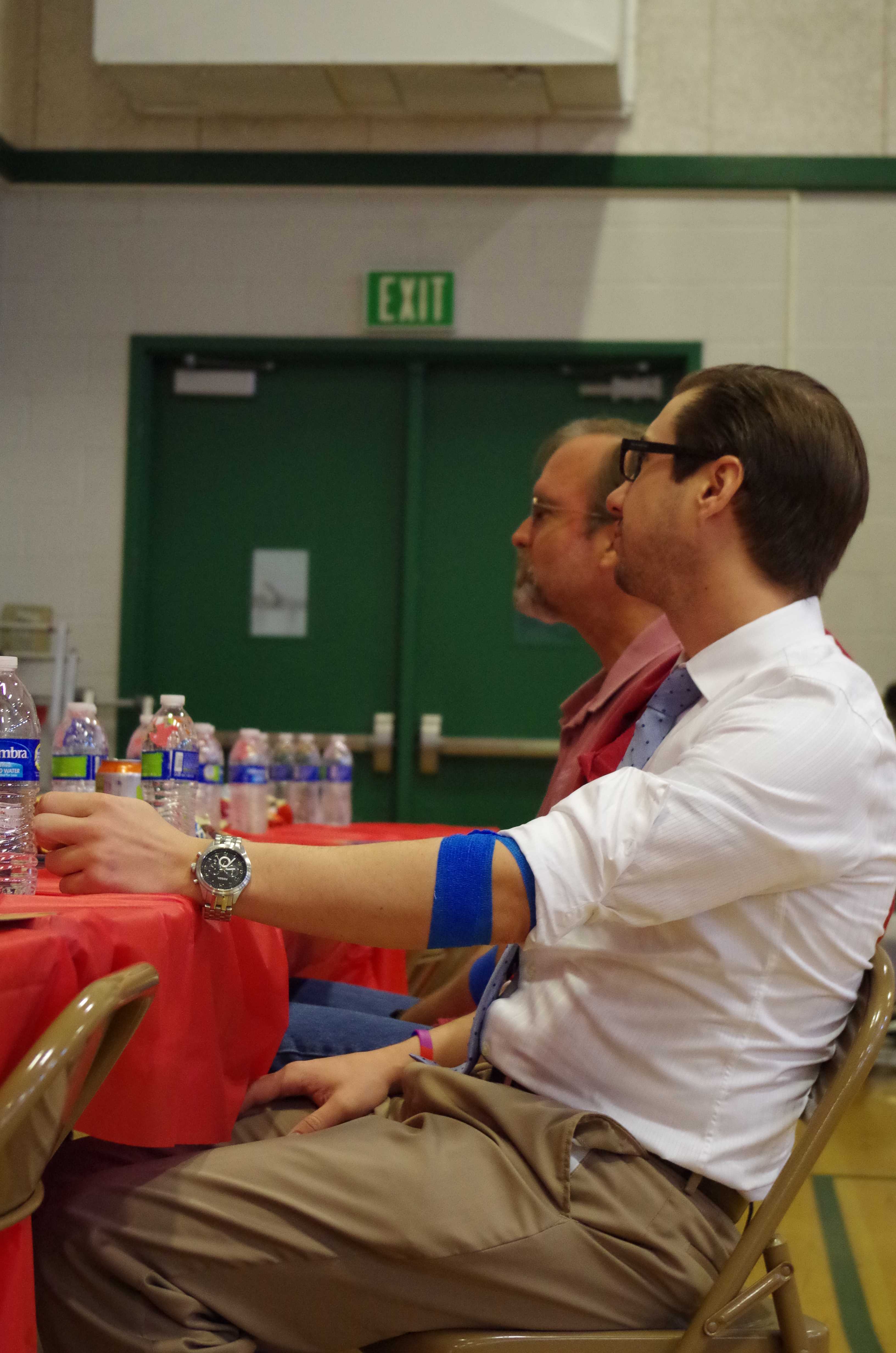EAT YOUR HEART OUT:  Although school is going on, Mr. Andrew Phillips eats cookies and drinks water with Mr. Scott Braly after successfully donating blood on May 23. Once you finish donating blood, Blood Source provides food and water for all volunteers to help avoid side effects of fatigue, dizziness, and various other side effects. “I donate because I have no reason not to. It could potentially save someone’s life and the only thing they ask is for twenty minutes of discomfort. It seems like an easy trade off.” Phillips said. Photo by Kristen Goldman