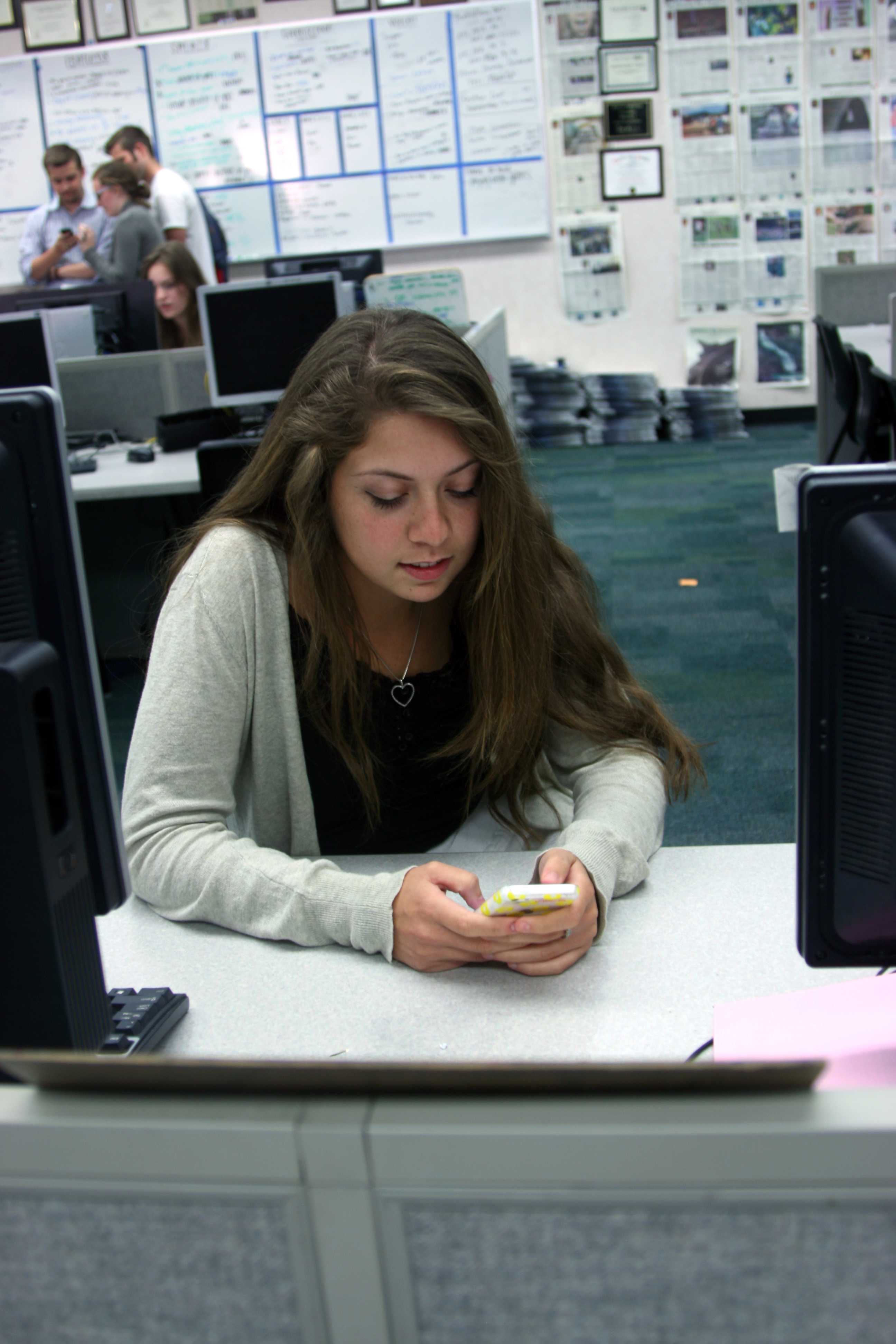 PROCRASTINATION NATION: Although homework needs to be finished, junior Lauren Helfer plays on her iPhone during lunch on April 23. Helfer tried to focus on her Psychology homework, but instead searched through Instagram."I procrastinate a lot, but it teaches me to finish a ton of work under a very limited time period so it can be useful, Helfer said. Photo by Ambreen Siddiqui
