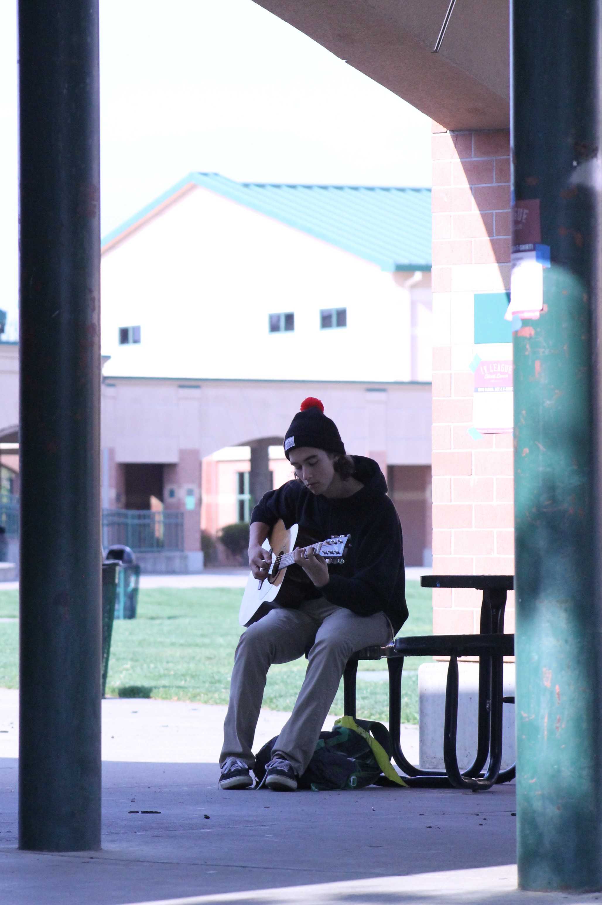 Although Guitar class can be very loud, senior Maxx Munzel finds a nice place to get away from the sound and focus on his strumming. “I try to escape the noise of other people playing as much as I can,” Munzel said. Photo by Sanjna Saini
