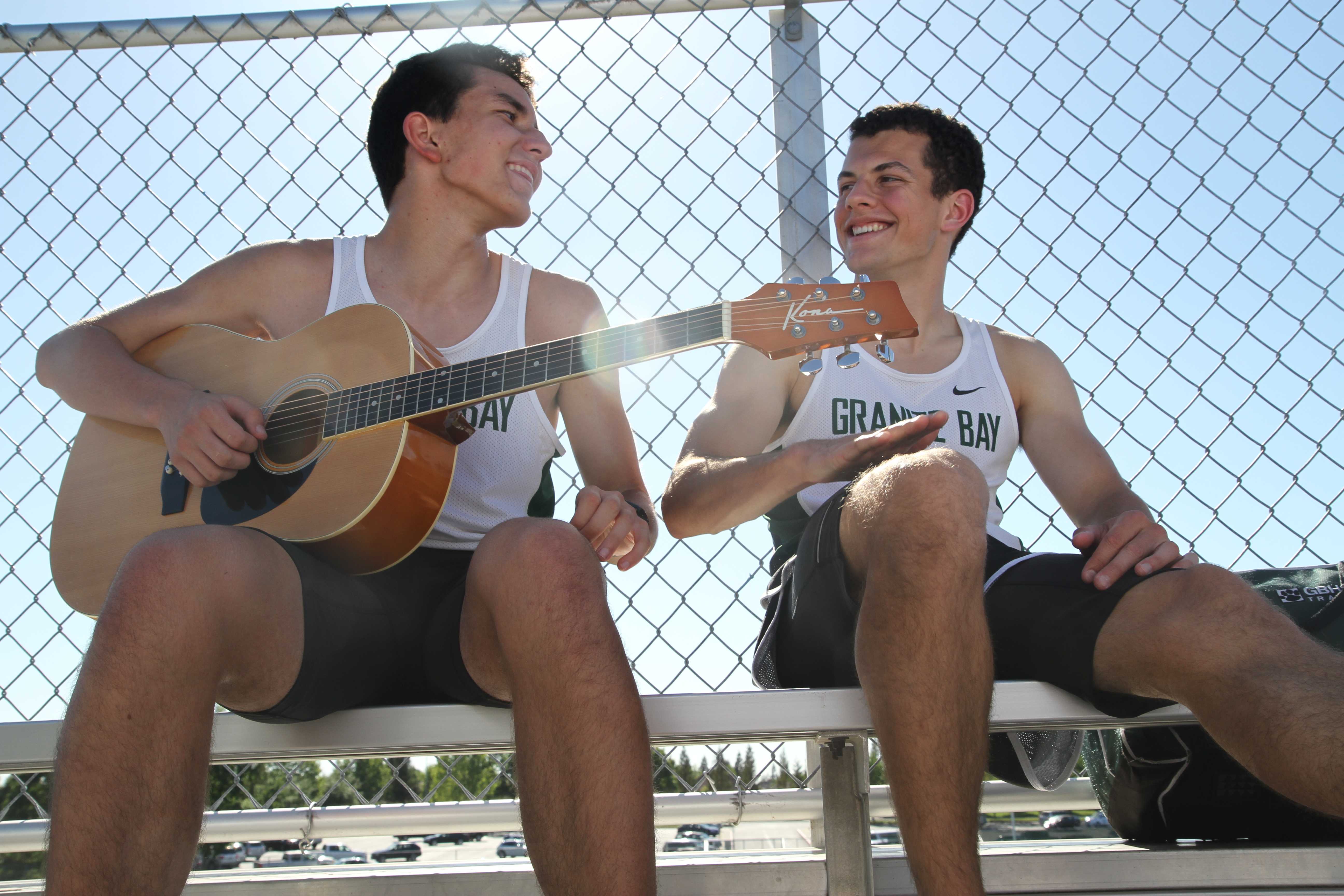 BETWEEN EVENTS While waiting for the two mile, during the home meet on April 29, junior Josiah Luna plays “Through the Fire and Flames” by Dragonforce, which surprises Junior Nathan Dell’Orto. According to Dell’Orto, “Through the Fire and Flames” is a really hard piece to play on the  guitar and for Luna to be able to play it, was fascinating. “It’s the song that everything gets compared to; if you can play is you’re basically a pro guitarist,” Dell’Orto said. Photo by Janelle Cruz